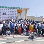 A group photo of persons with and without disabilities standing on steps of a hotel